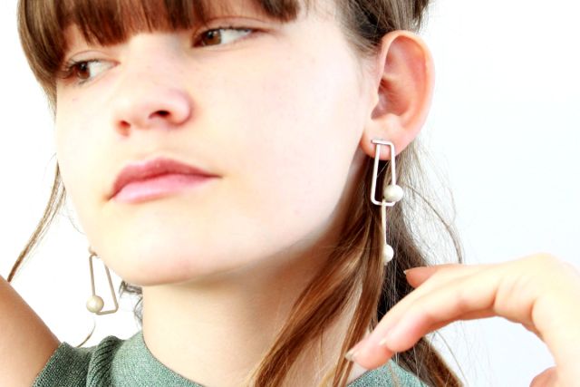 Model mit Trapez-Ohrringen mit Perle