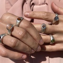 Klassisch, kompakter Ring aus Silber mit rundem, lachsfärbigen Mondstein mit Cabochon-Schliff, gemeinsam mit anderen Ringen, getragen.