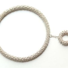Romantischer, runder Armreif aus Silber mit beweglichem, ringförmigem Anhänger. Die textil anmutende Oberflächenstruktur, ergibt sich durch eine bewegliche Kette, die um einen inneren Kern gewickelt ist.