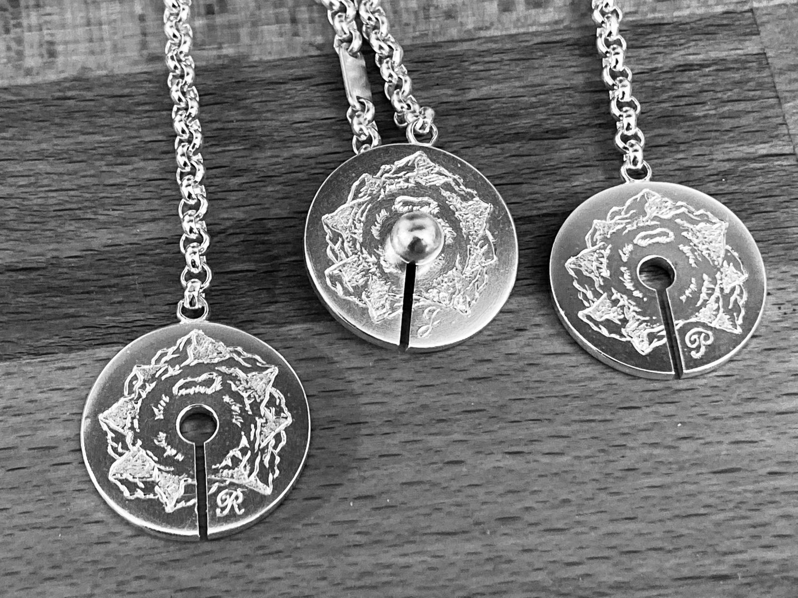 Drei handgravierte, runde Schlüsselanhänger aus Silber.